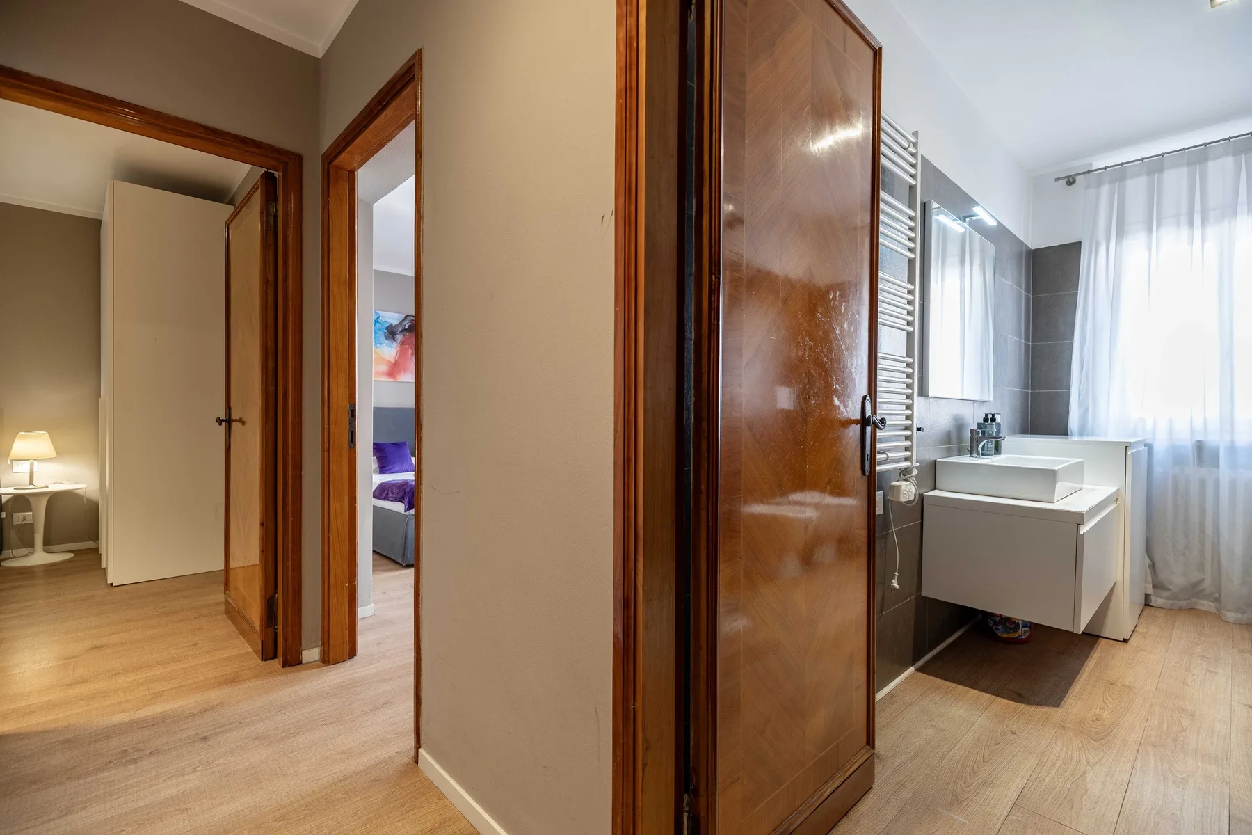 A hallway opens onto a bathroom with a bathtub and a bedroom beyond.
