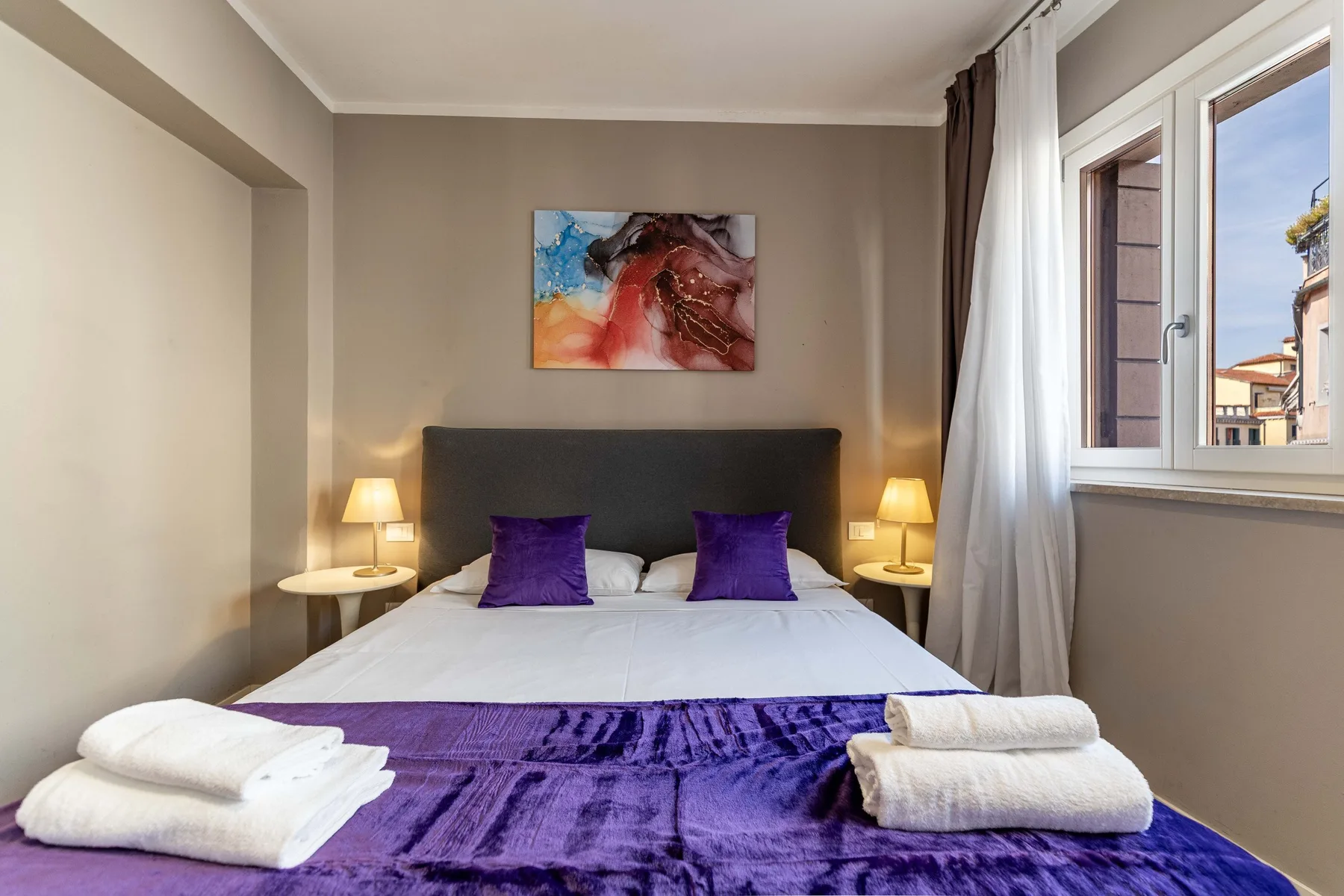 A bedroom with a neatly made bed and purple bedding.