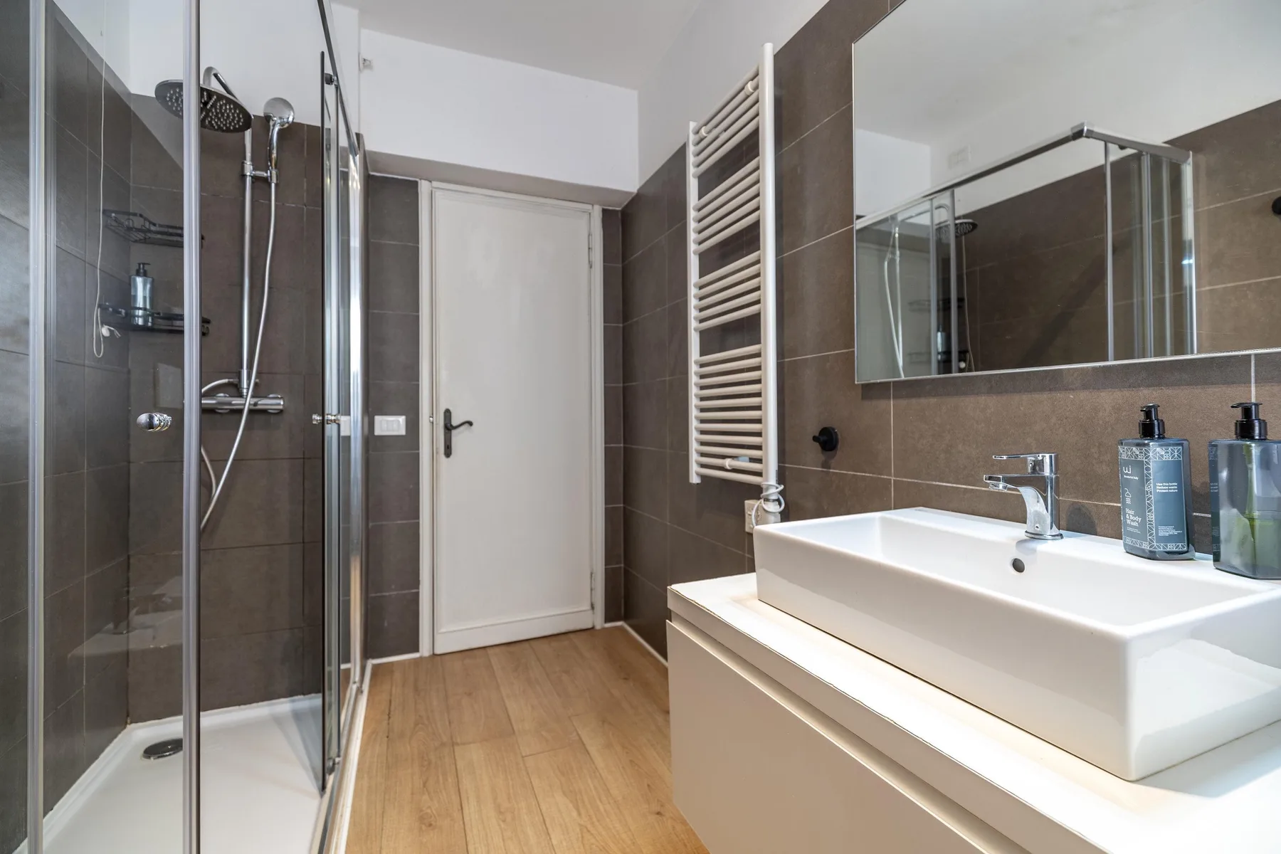 A modern bathroom with a glass shower, sink, and wall mirror.