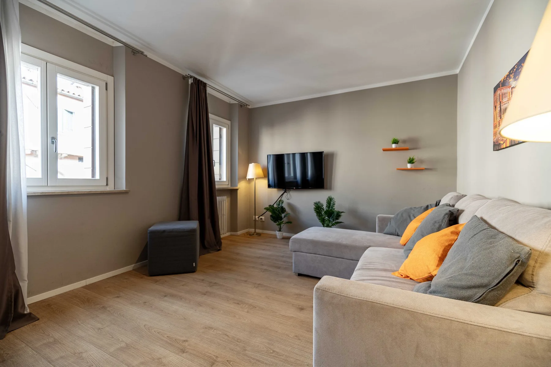 A living room with a sectional sofa, television, and large windows.