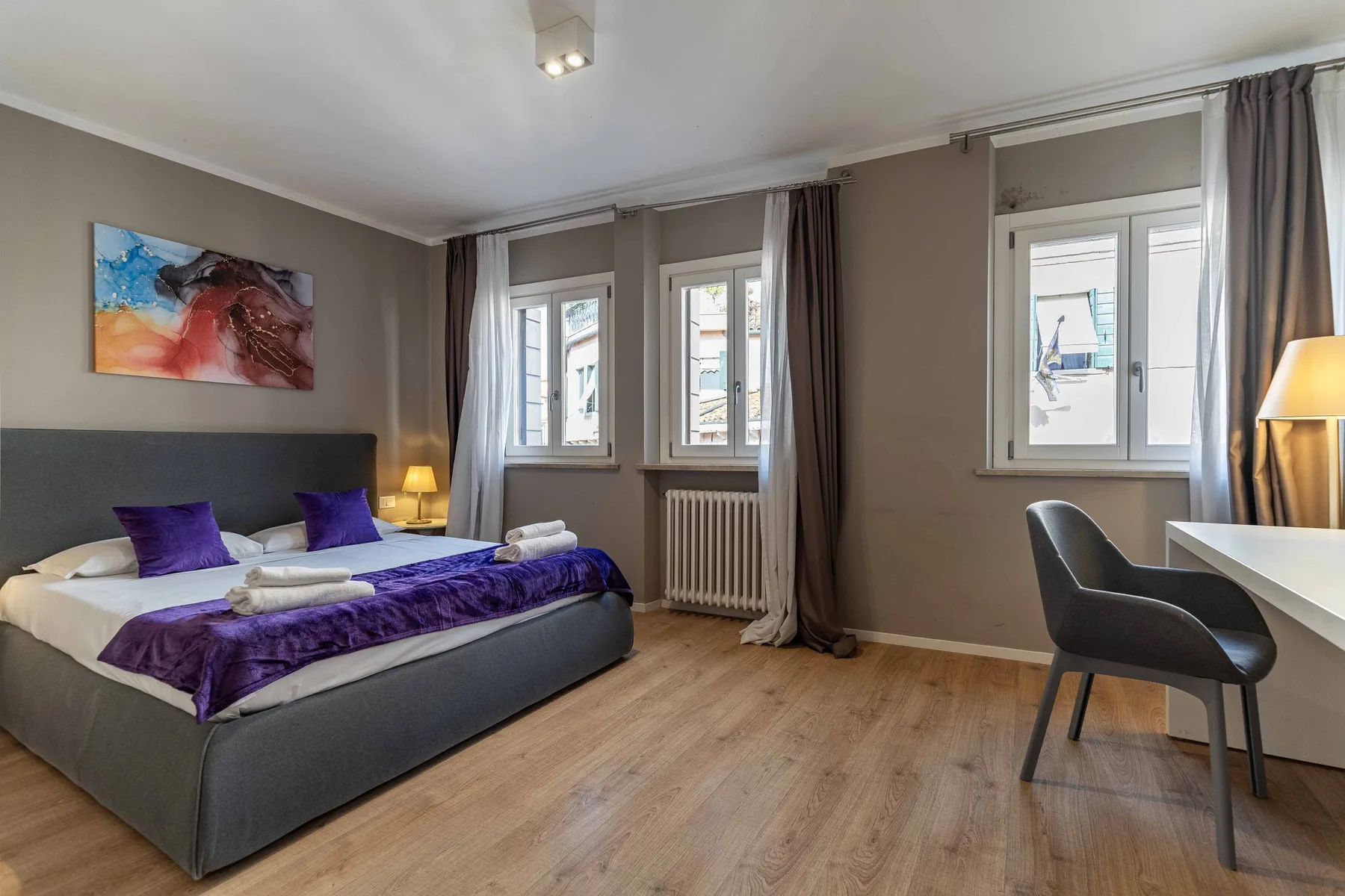 A bedroom with a bed, windows, and a small desk area.