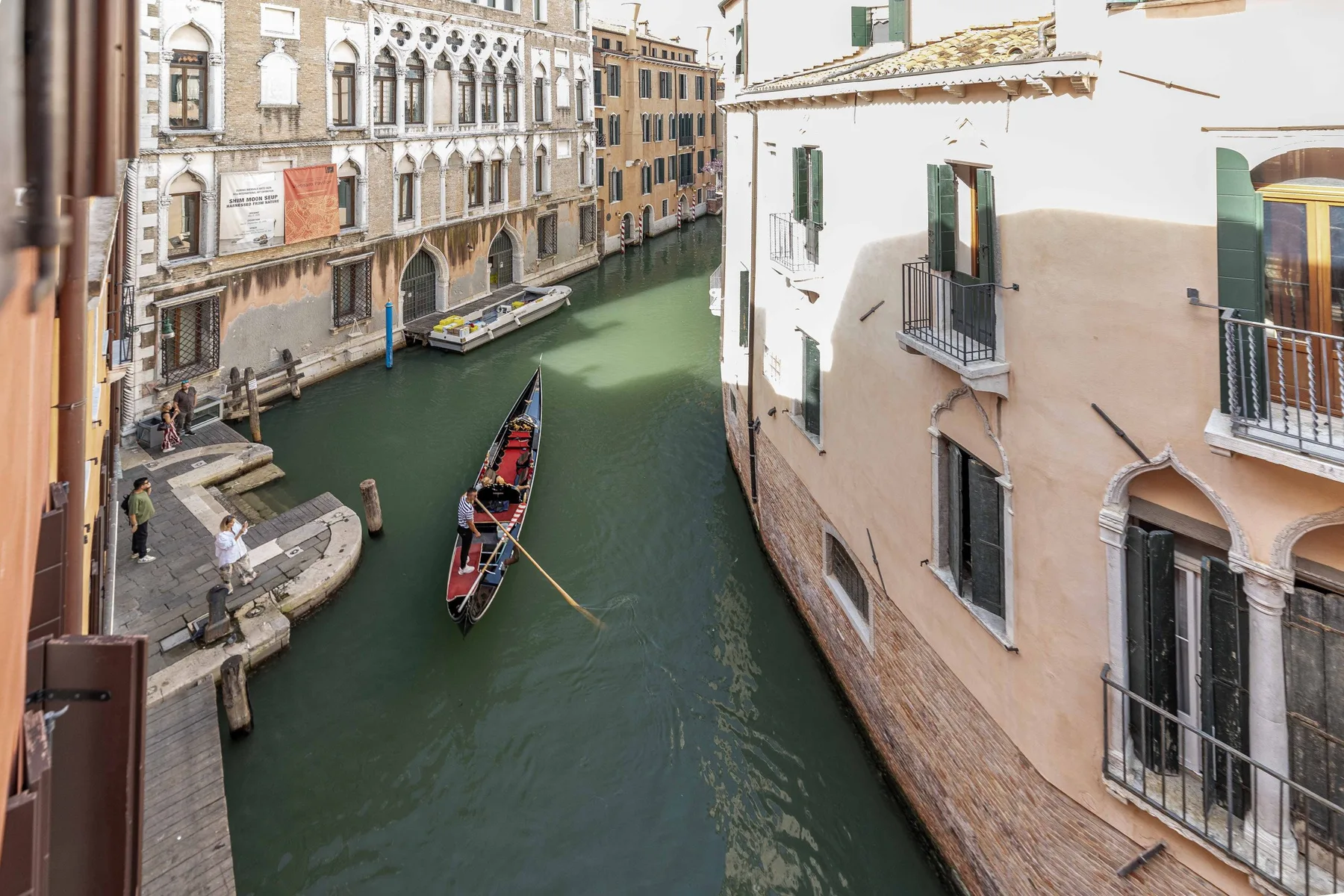 A narrow canal runs between old buildings, with small boats on the water.