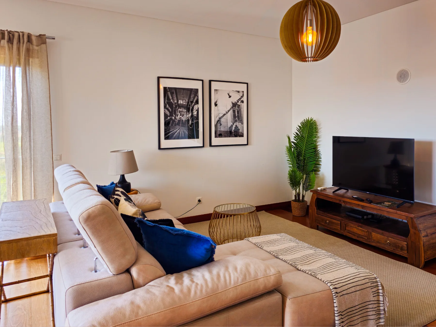 A living room with seating, a television, and framed wall art.