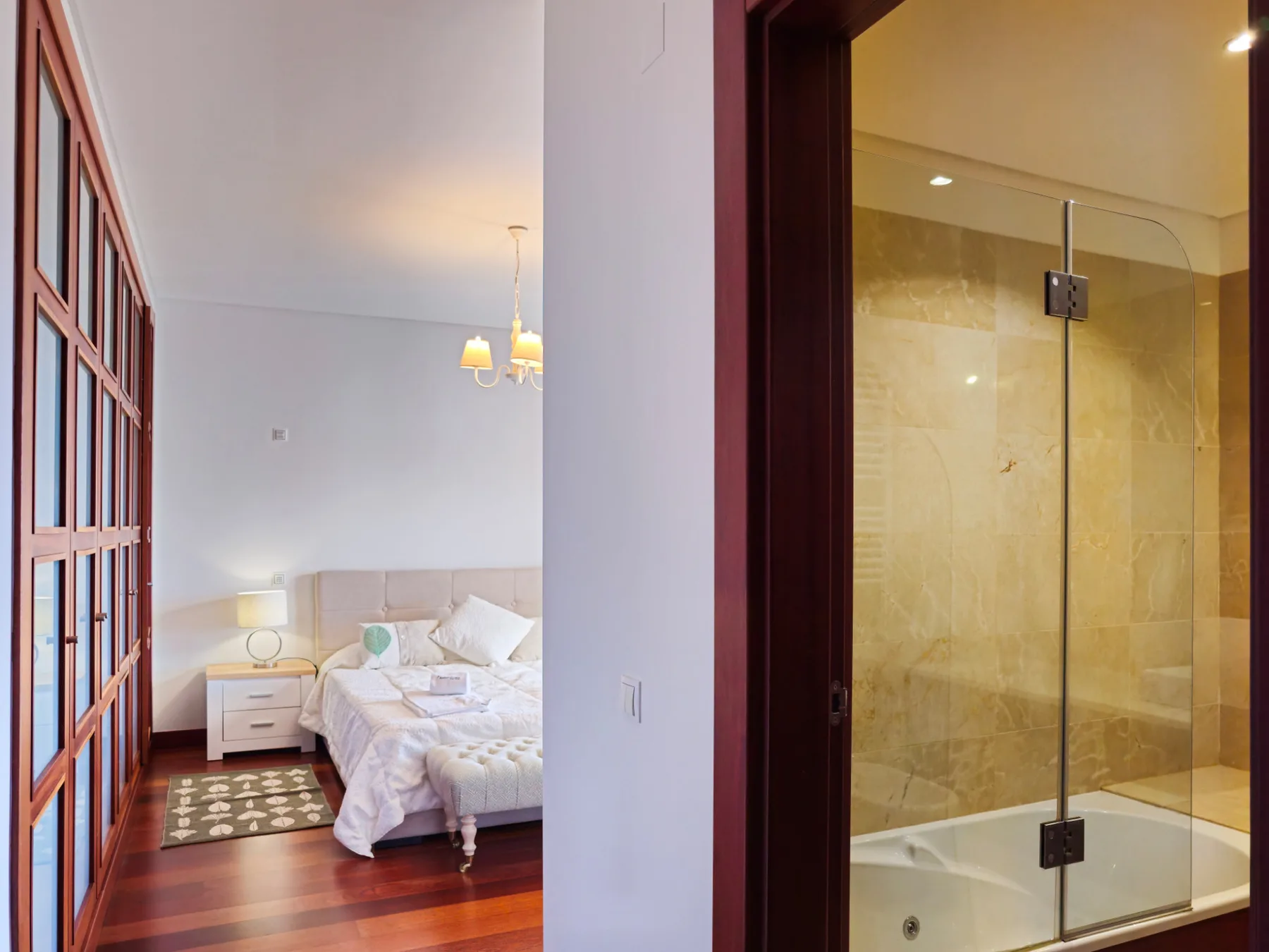 A bedroom with a bed and bedside table beside an adjoining bathroom.