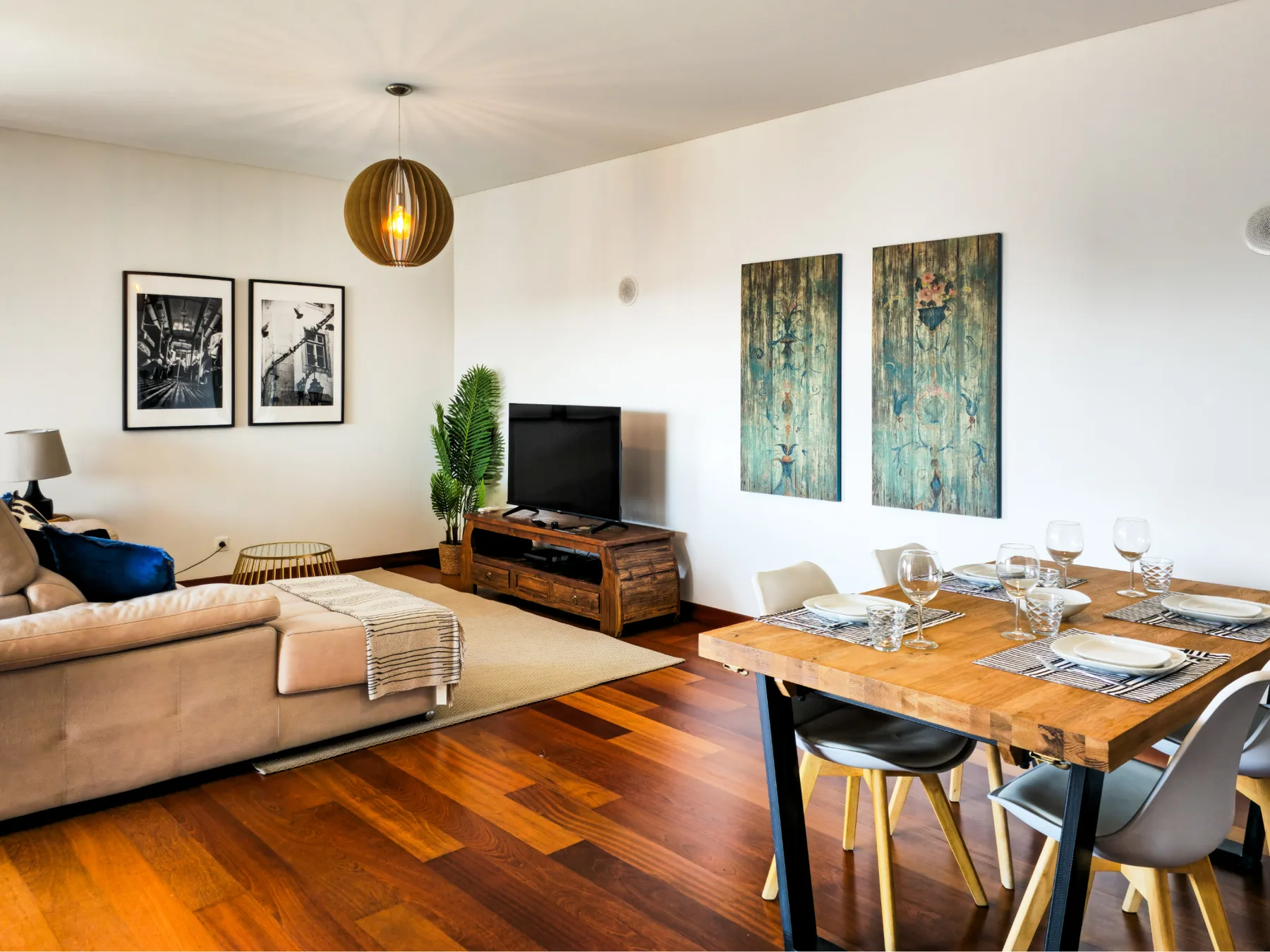 A living and dining area with a television, seating, and a wooden table.