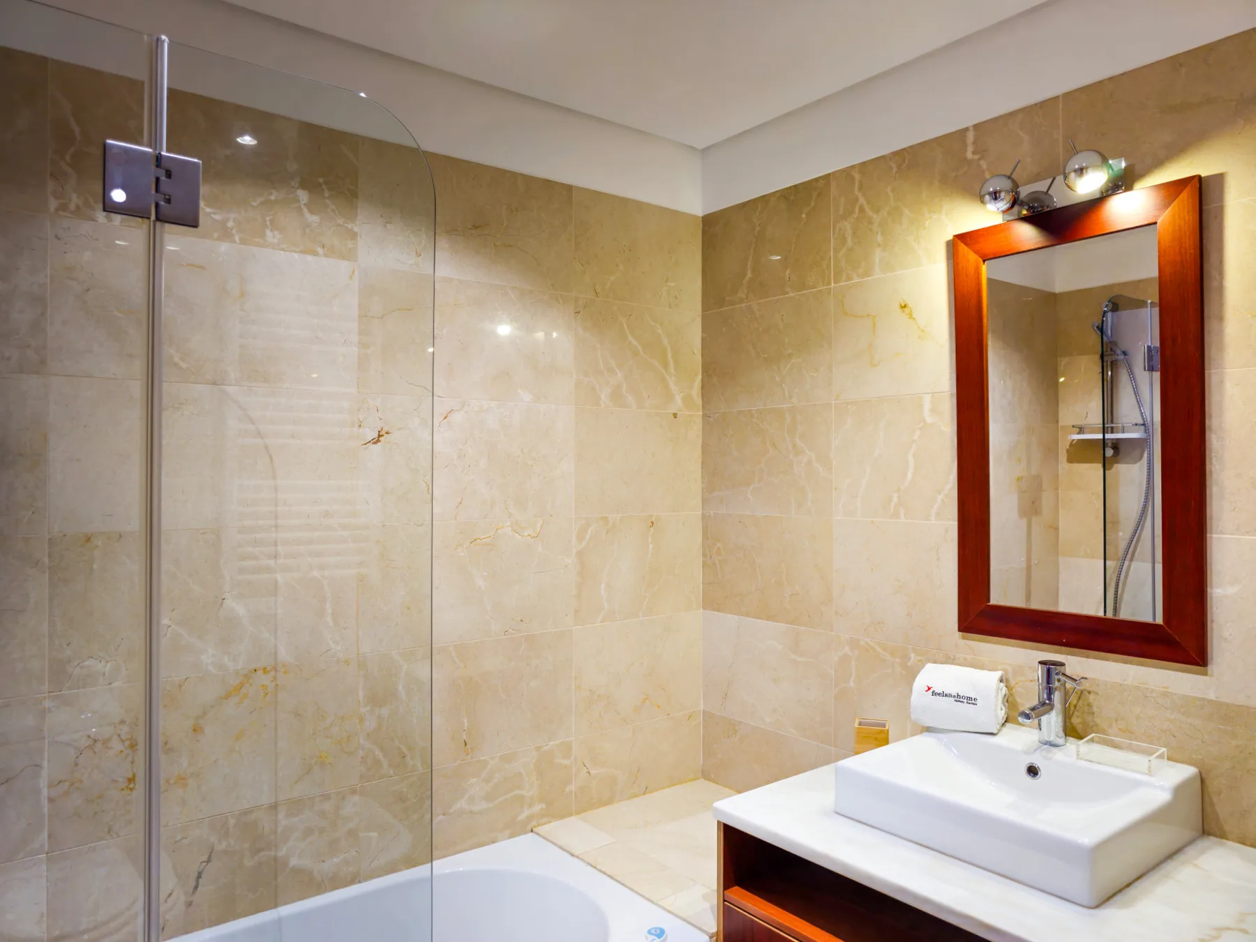 Un baño con una ducha de vidrio y un lavabo bajo un espejo.