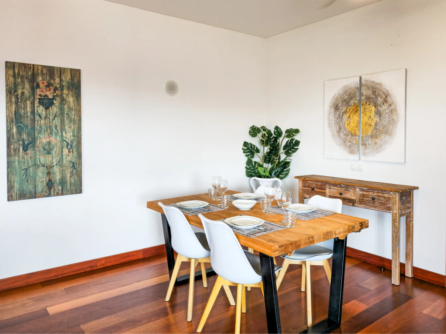 A dining area with a wooden table set with plates and chairs.