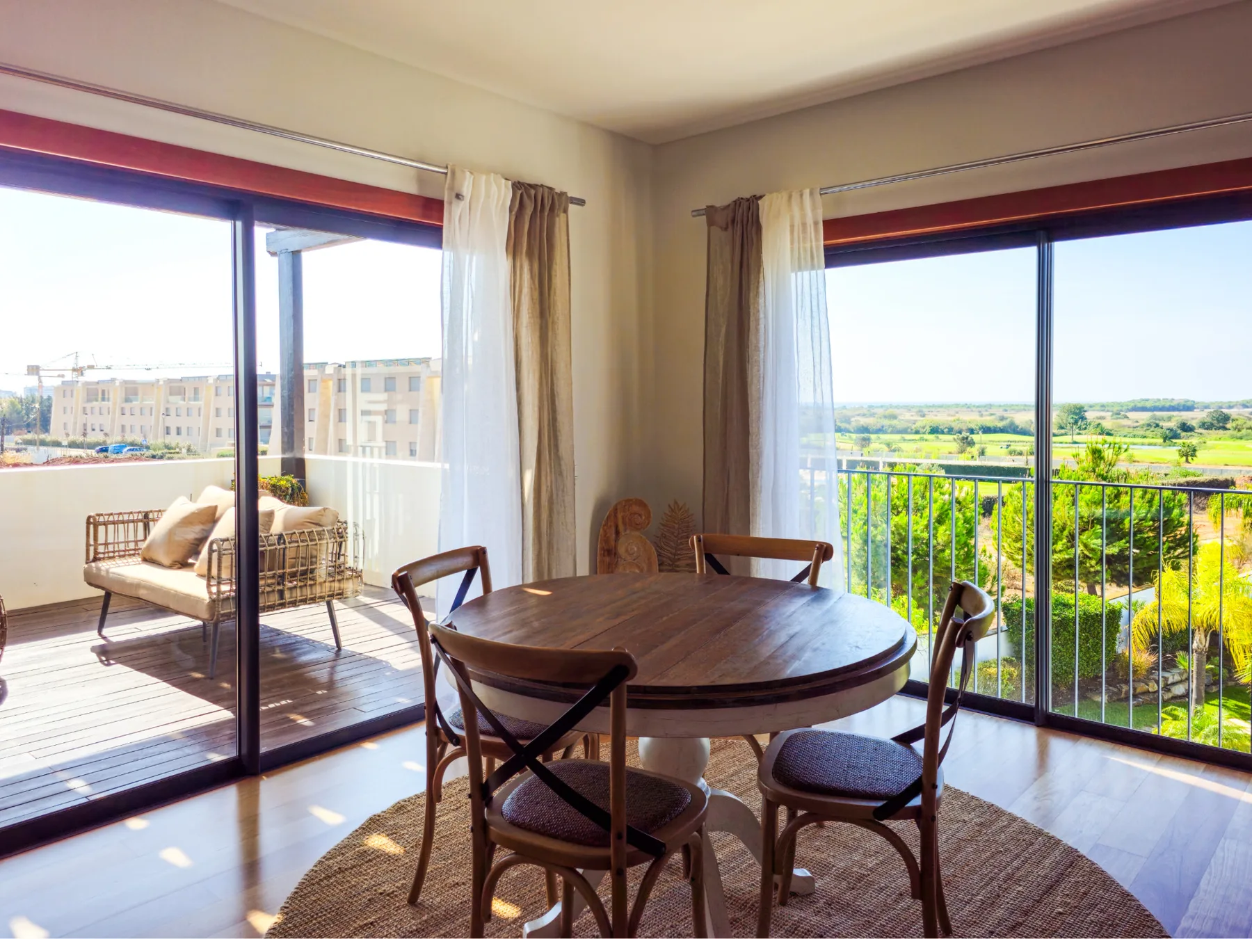A dining area with a round table and chairs beside glass doors opening onto a balcony.