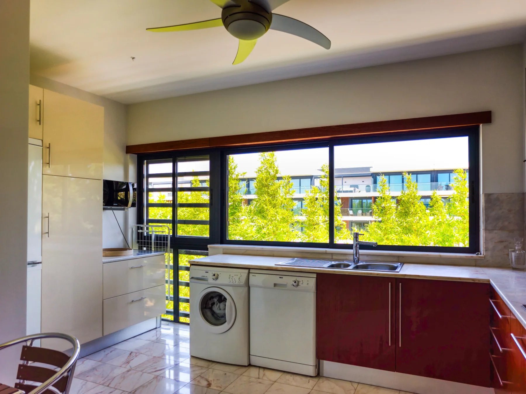 Una cocina luminosa con gabinetes inferiores rojos y una ventana amplia.