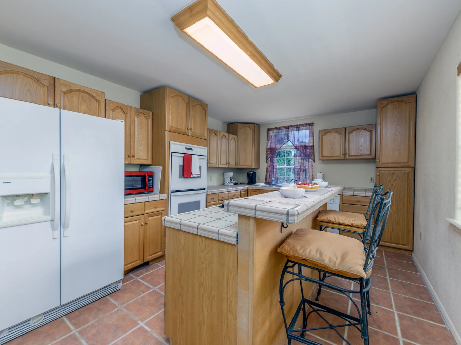 Una cocina con gabinetes de madera, una isla central y asientos altos.