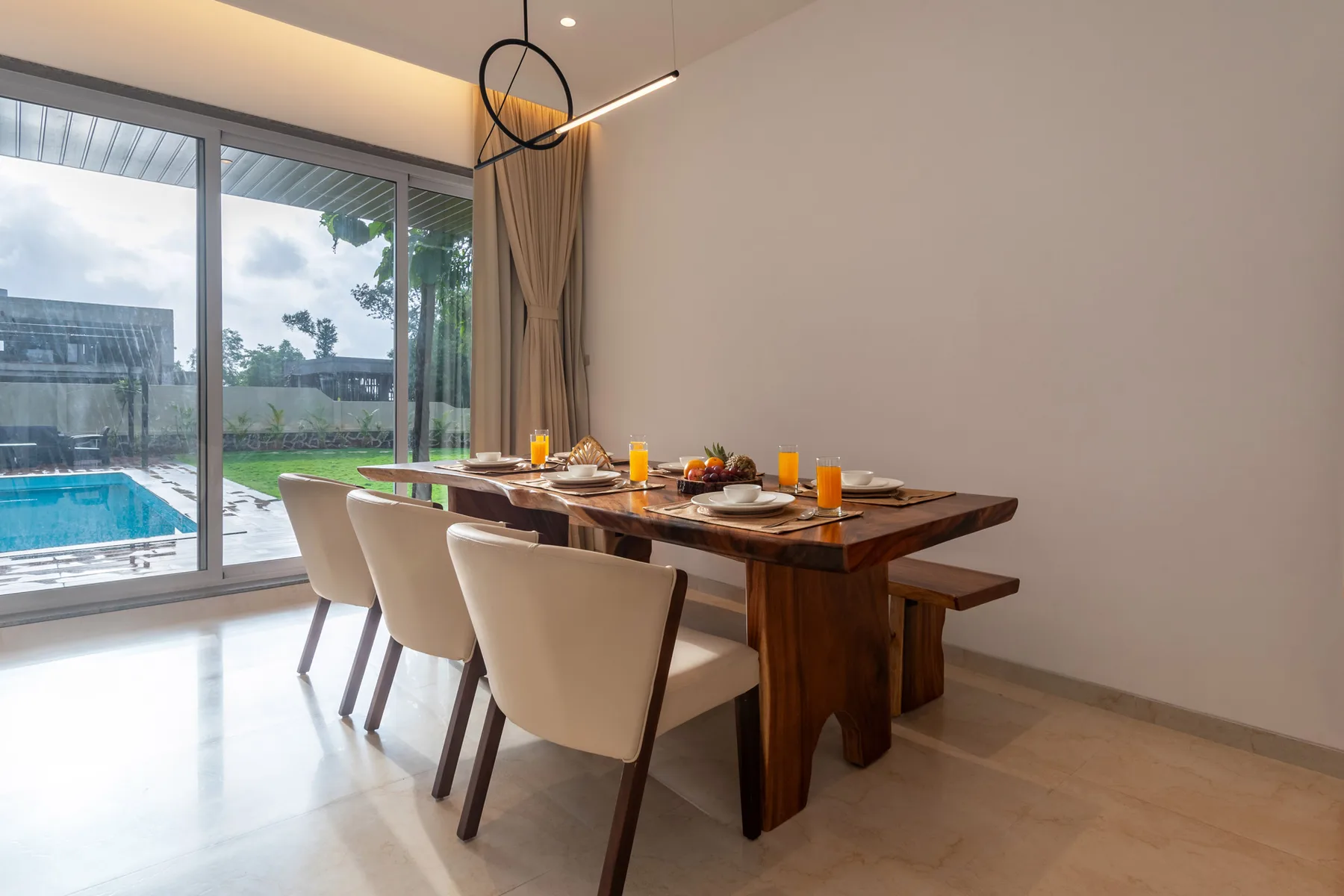 Un comedor con una mesa larga junto a grandes puertas de vidrio con vista a una piscina.