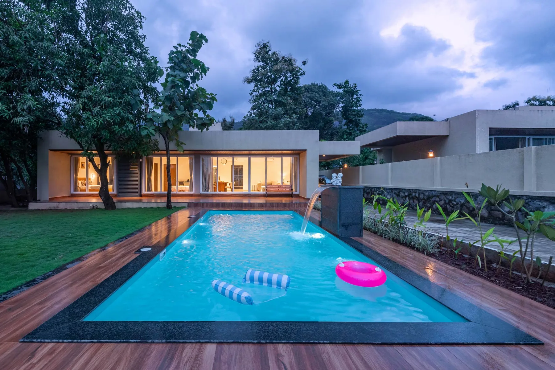 Una piscina junto a una casa moderna, con un flotador rosa en el agua.