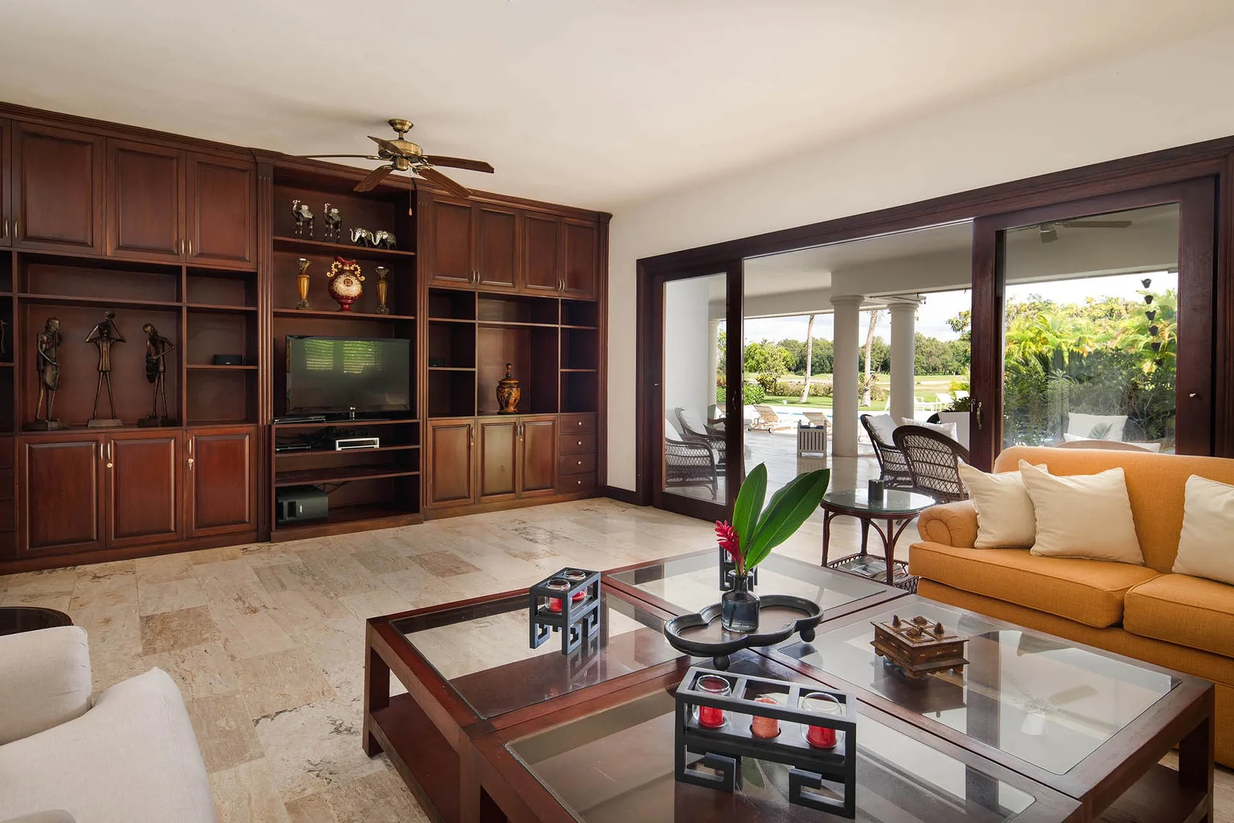 A living room with dark built-in cabinetry, a television, and seating beside glass doors.