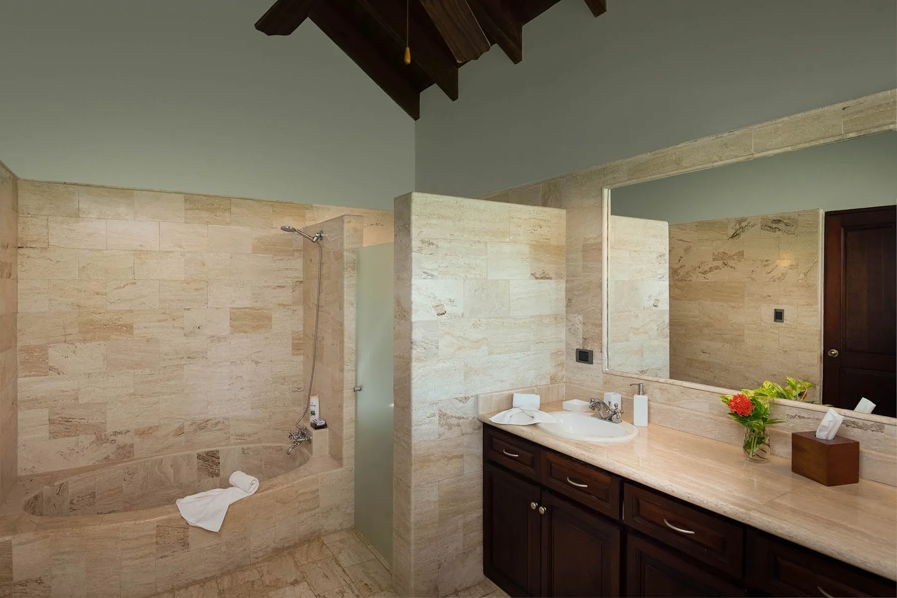 A bathroom with a walk-in shower and a vanity topped by a large mirror.