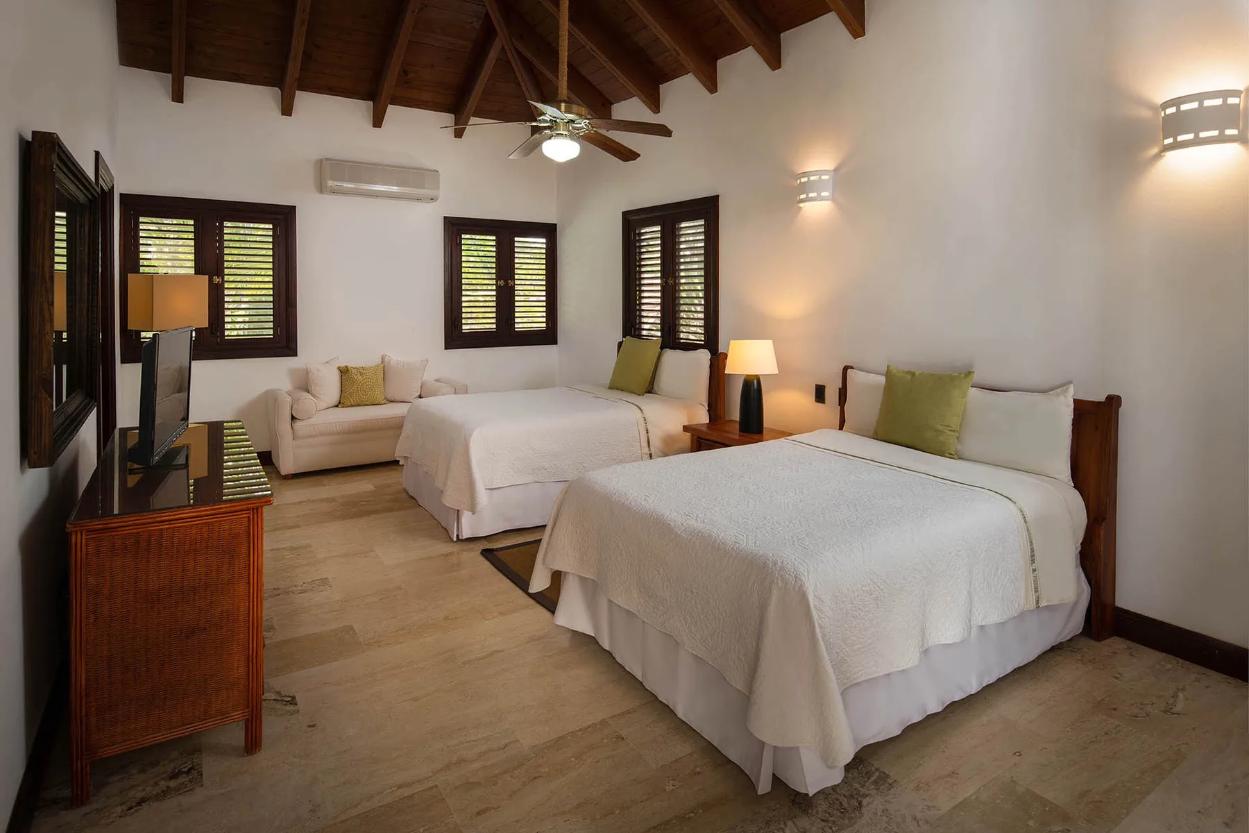 A bedroom with two beds, bedside lamps, and shuttered windows.