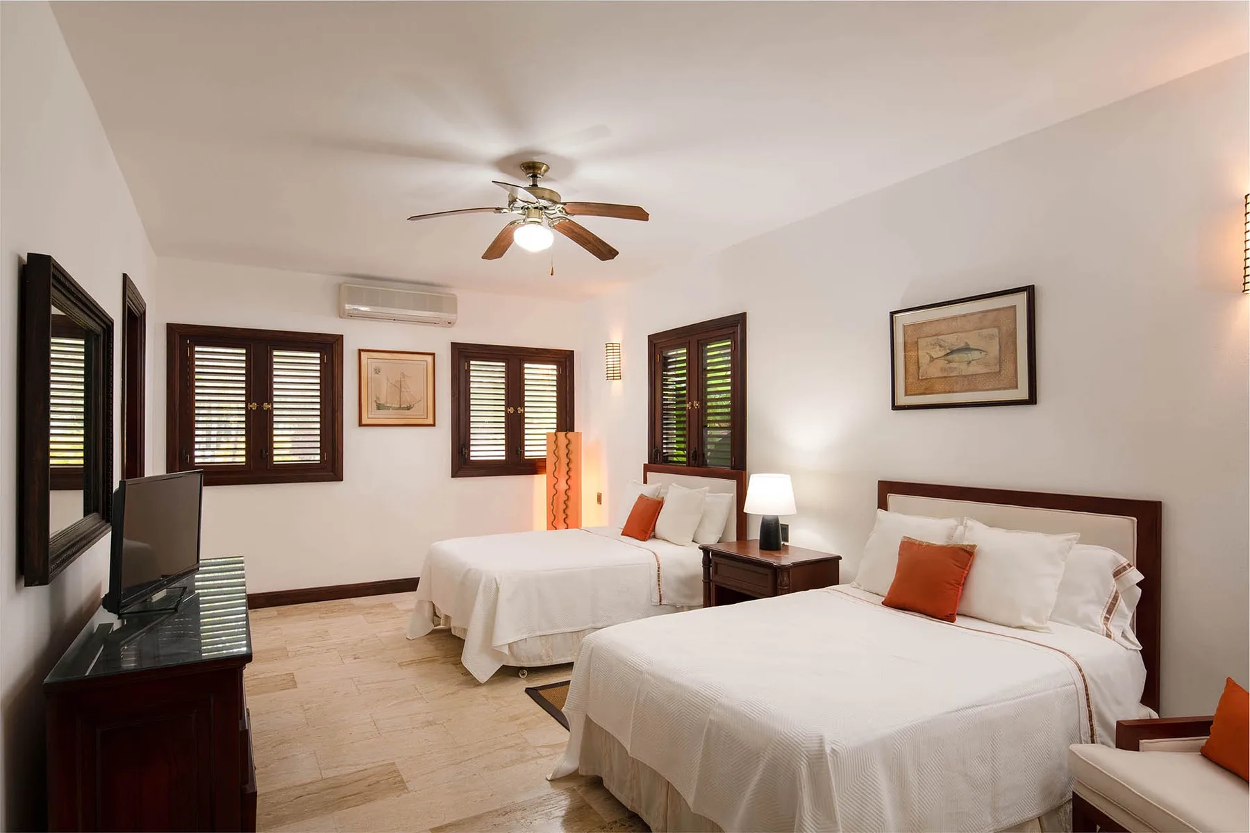 A bedroom with two beds, dark window shutters, and a ceiling fan.