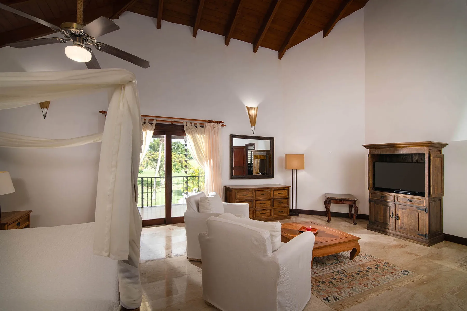 A living room with pale seating, a wooden coffee table, and doors opening to a balcony.