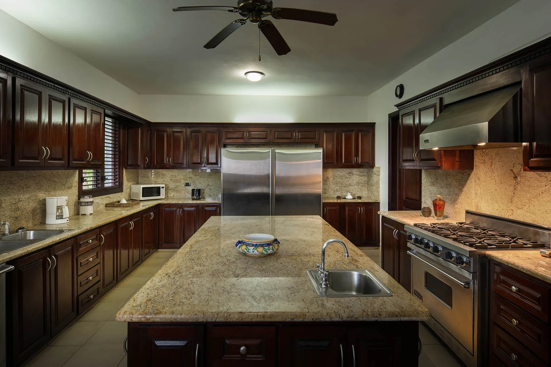 A spacious kitchen with dark cabinets, a central island, and stainless steel appliances.