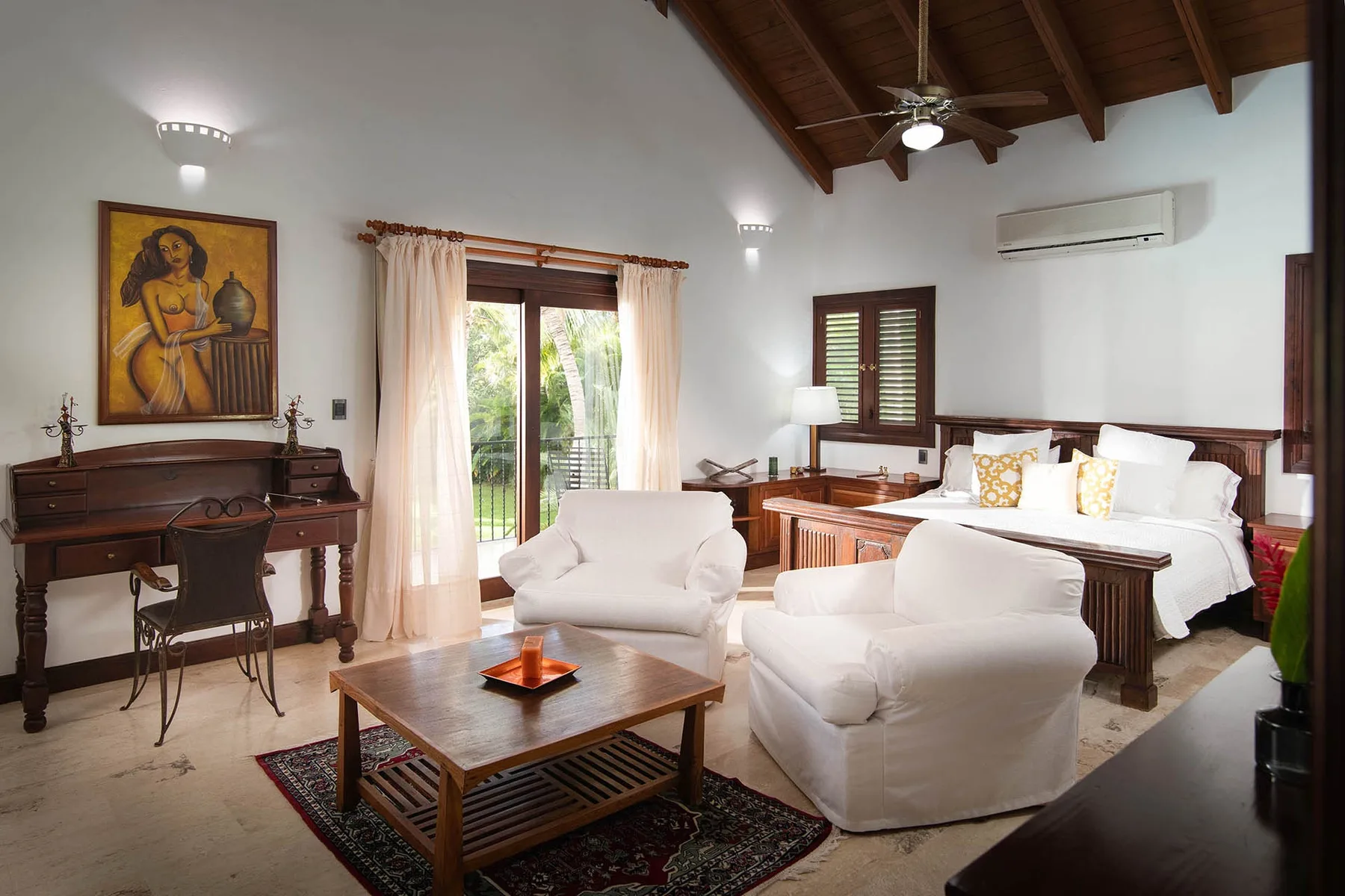 A bedroom with a writing desk, seating, and a wooden coffee table.