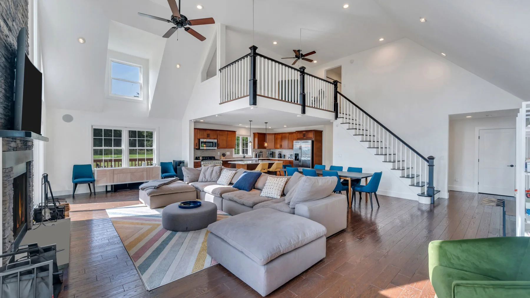 An open living room with seating, a rug, and a kitchen beyond.