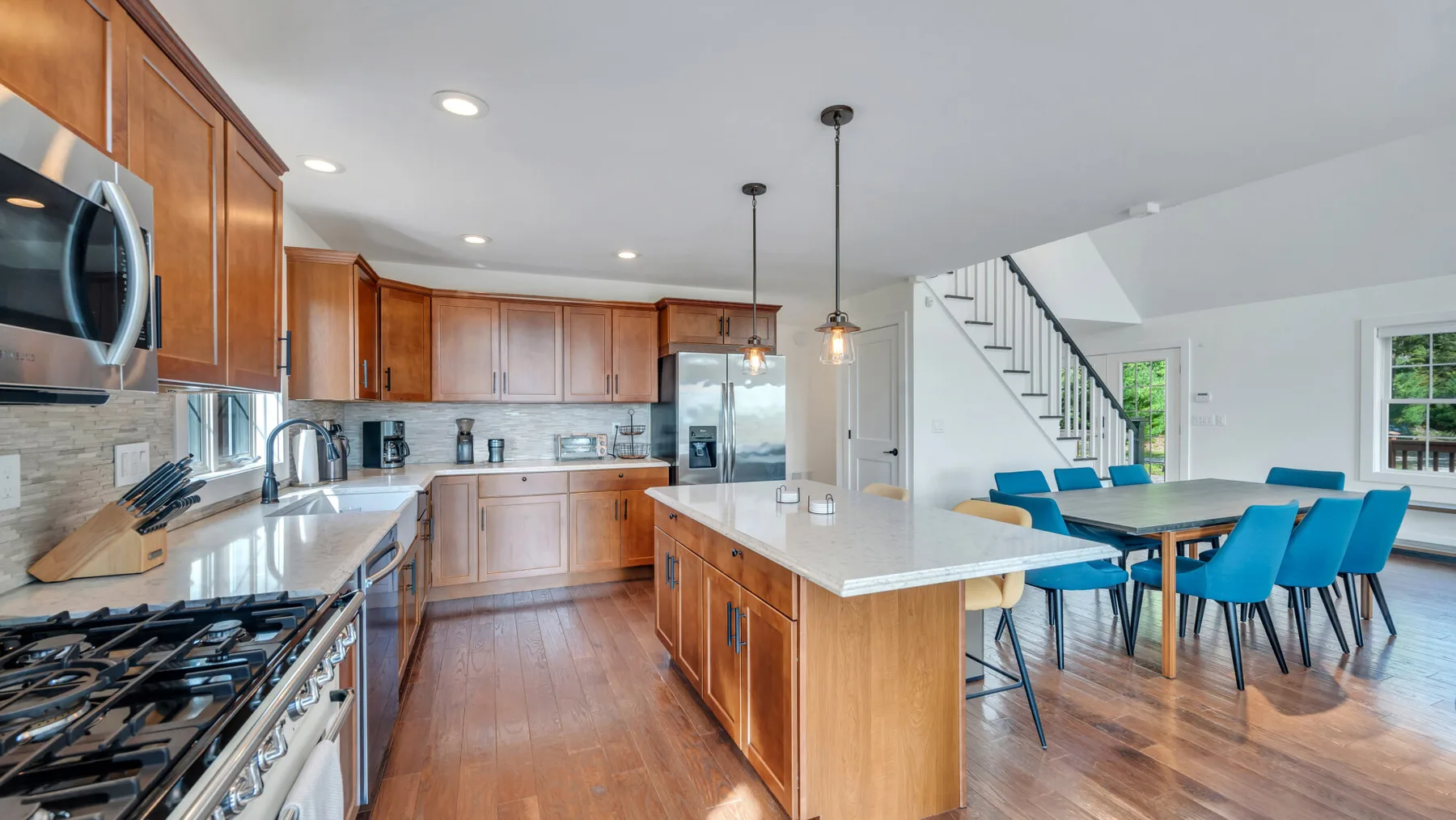 An open kitchen and dining area with wooden cabinetry and a table beside the stairs.