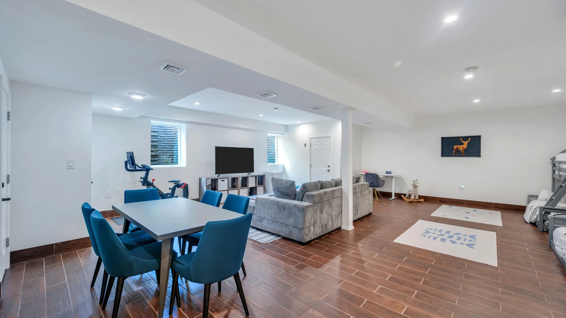 A bright living and dining area with a table, blue seating, and a television.