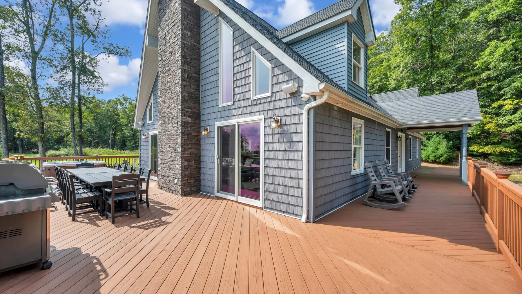 A spacious wooden deck beside a house, with outdoor dining and seating areas.