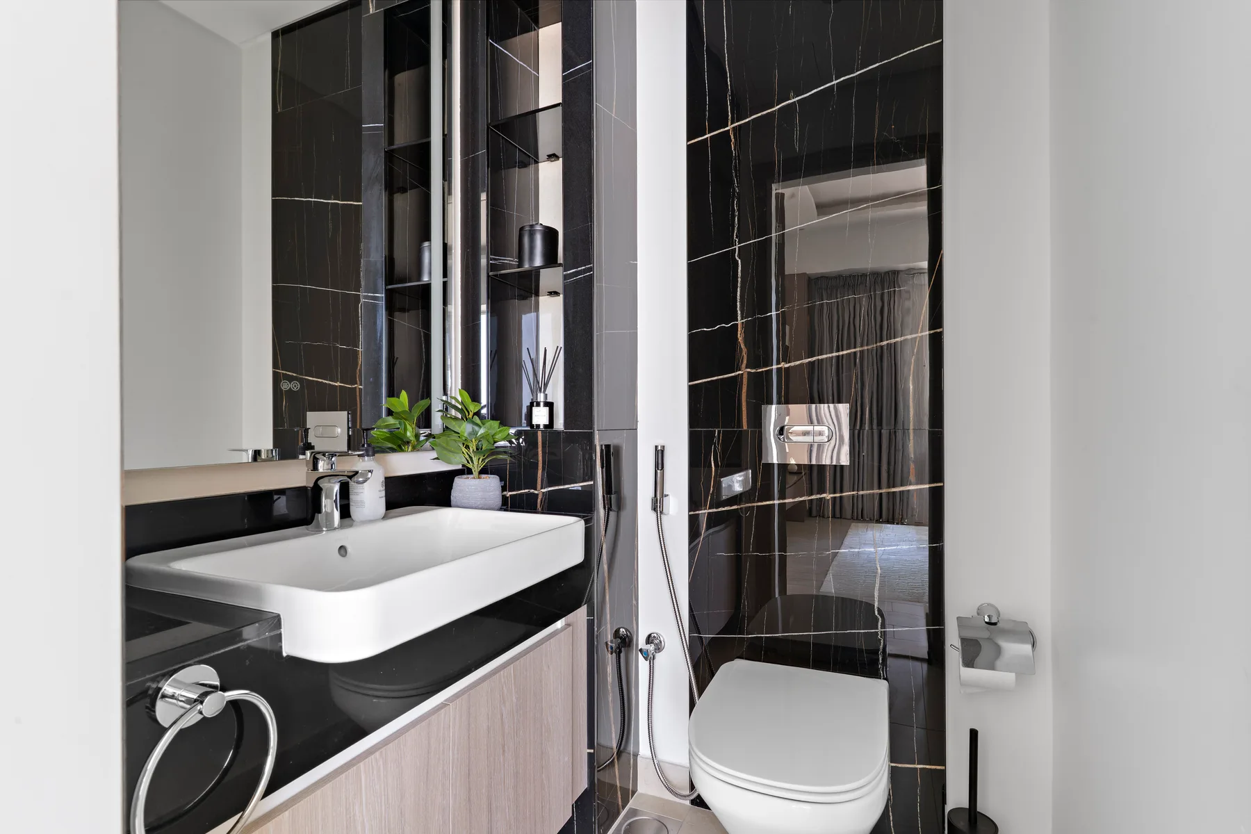 Un baño moderno con lavabo blanco, espejo e inodoro.