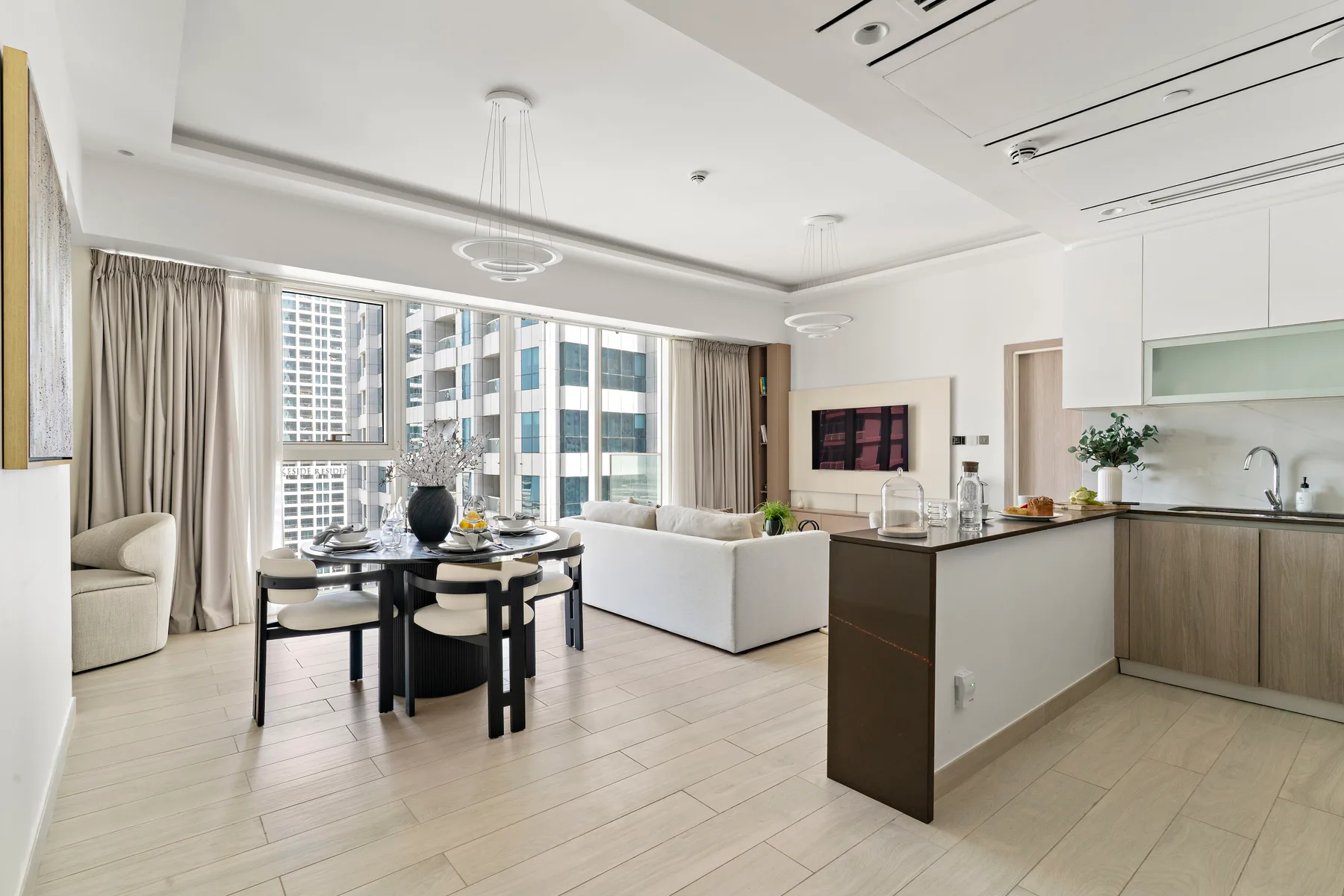 Una luminosa sala-comedor de planta abierta con una isla de cocina y grandes ventanales.