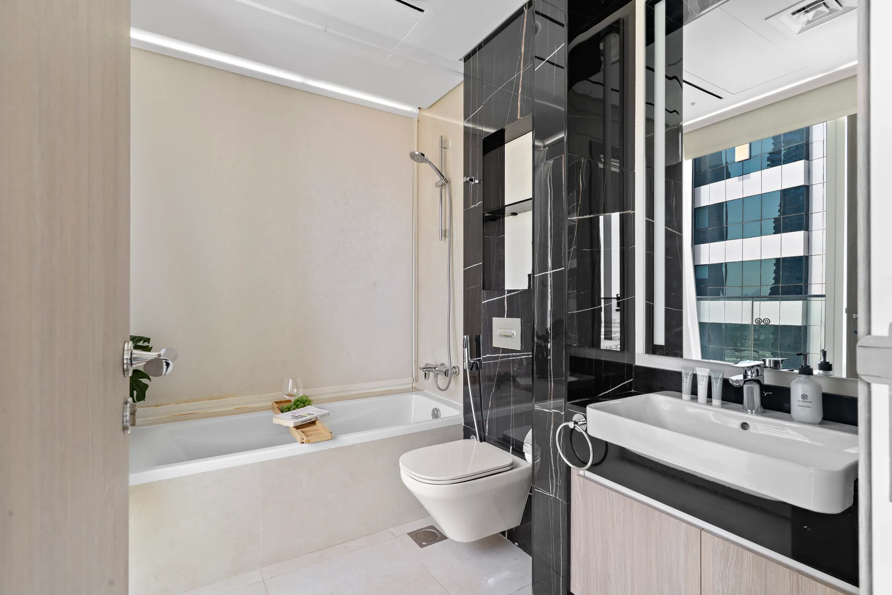Un baño moderno con bañera, inodoro y tocador con lavabo.