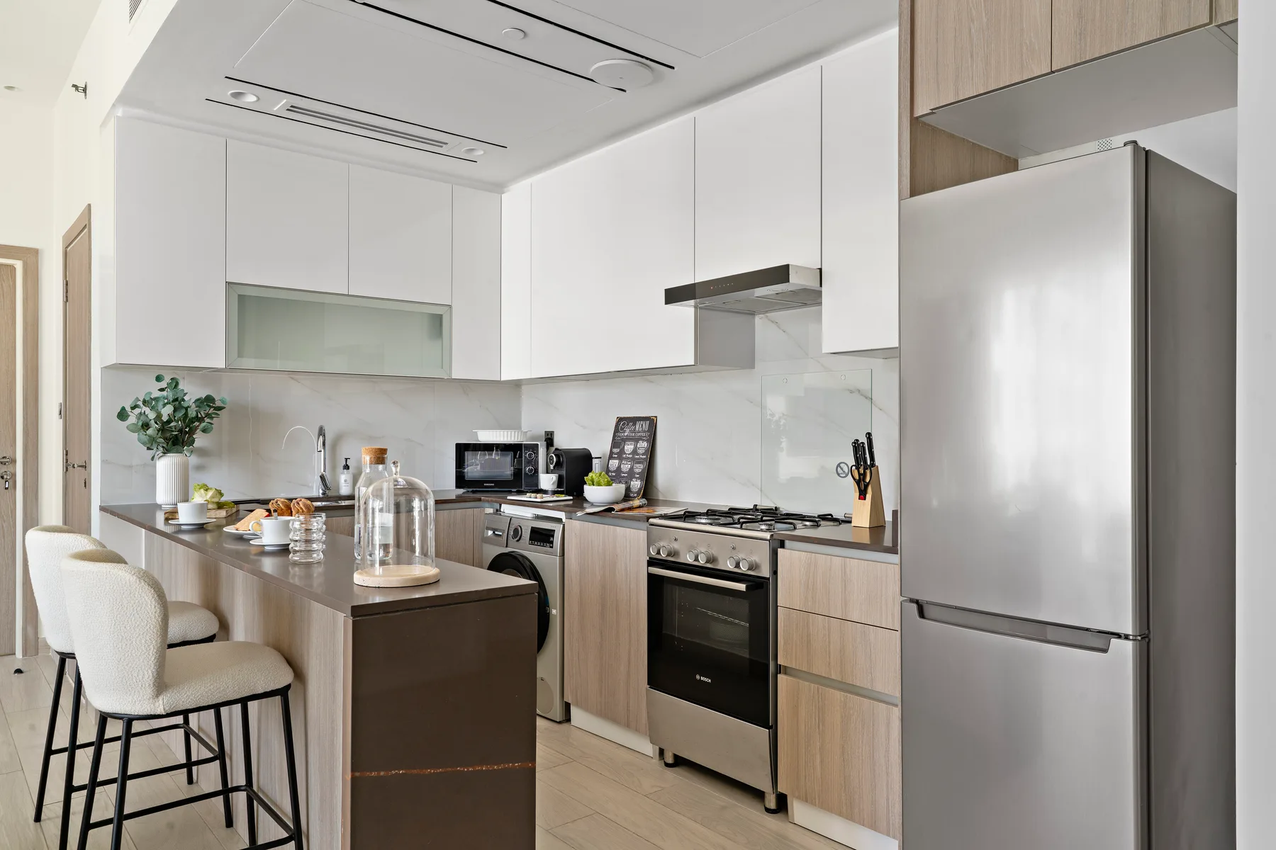 Una cocina moderna con una isla de encimera, gabinetes claros y electrodomésticos de acero inoxidable.