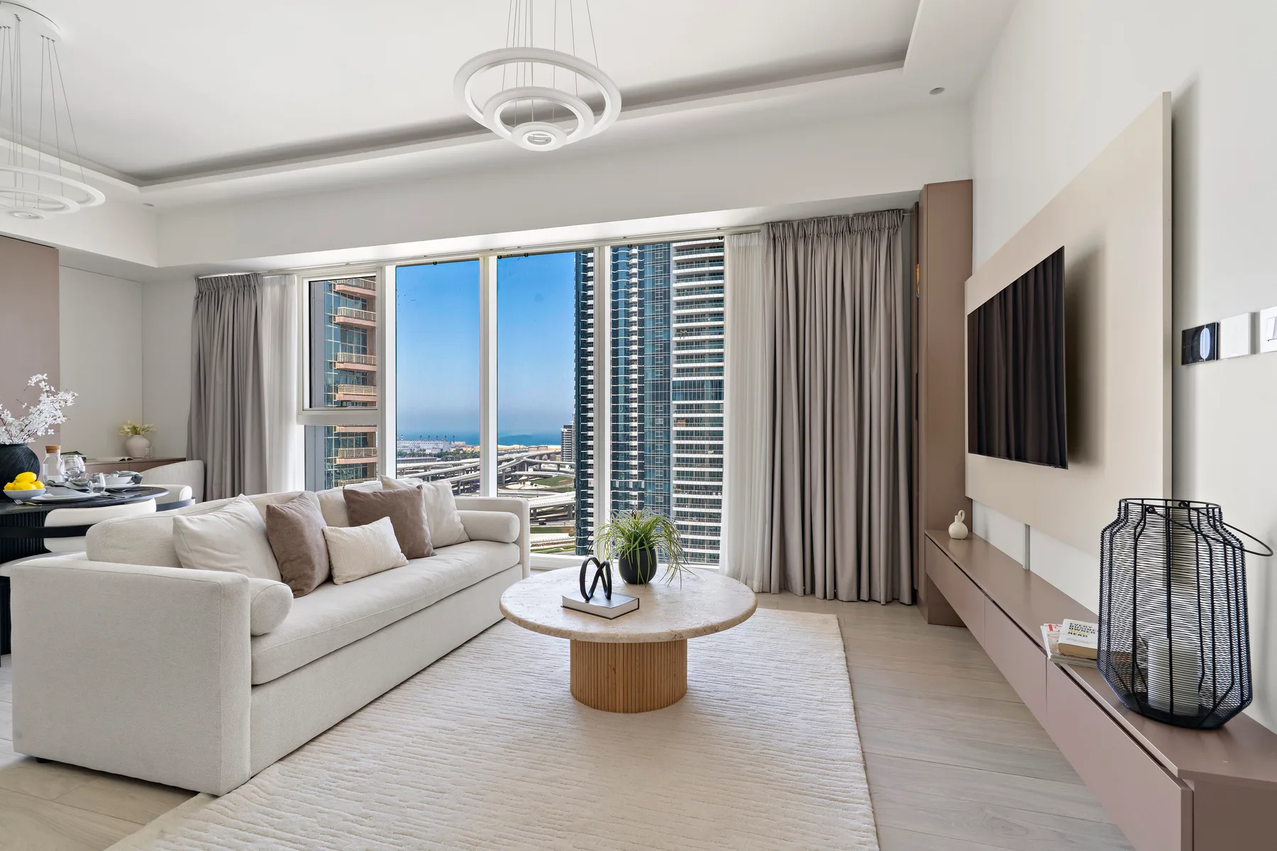 Una sala luminosa con asientos blancos y grandes ventanas con vistas a edificios altos.