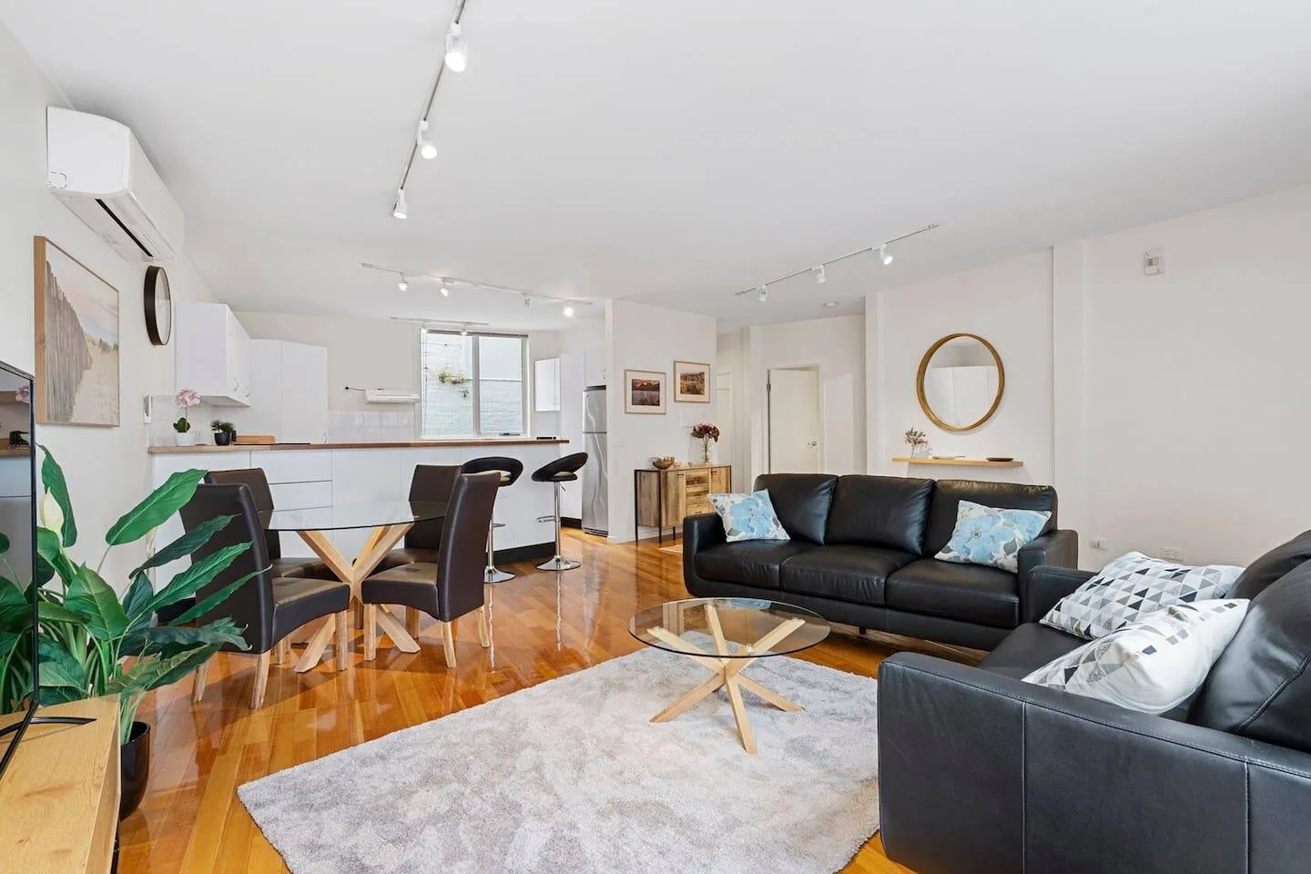 Open-plan living and dining area with black seating and a light-colored rug.