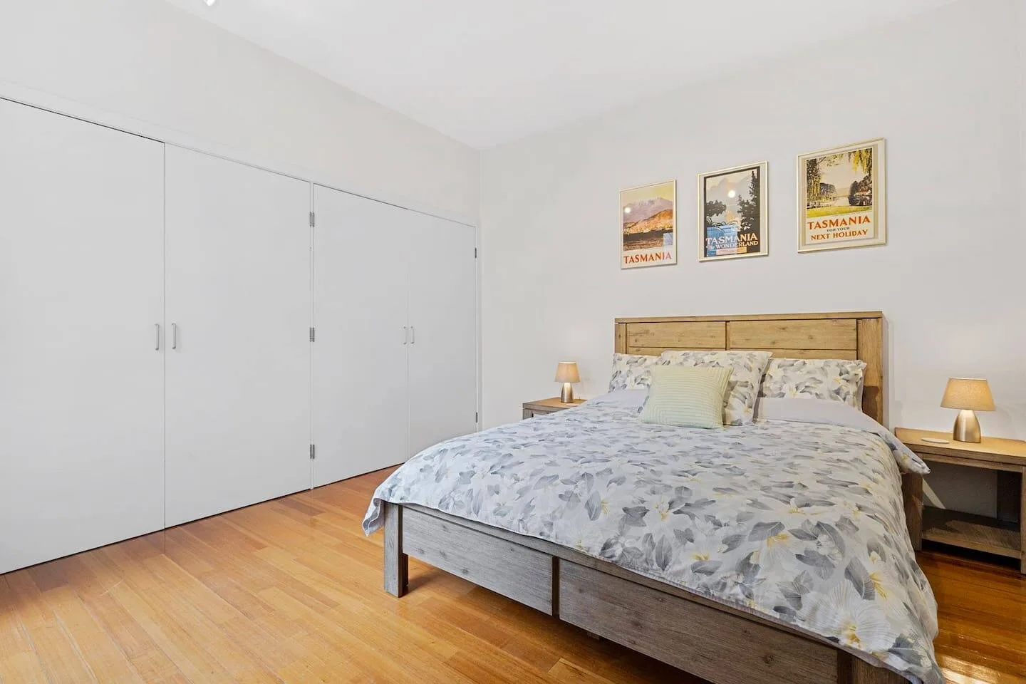 Un dormitorio con una cama, mesitas de noche y armarios empotrados.