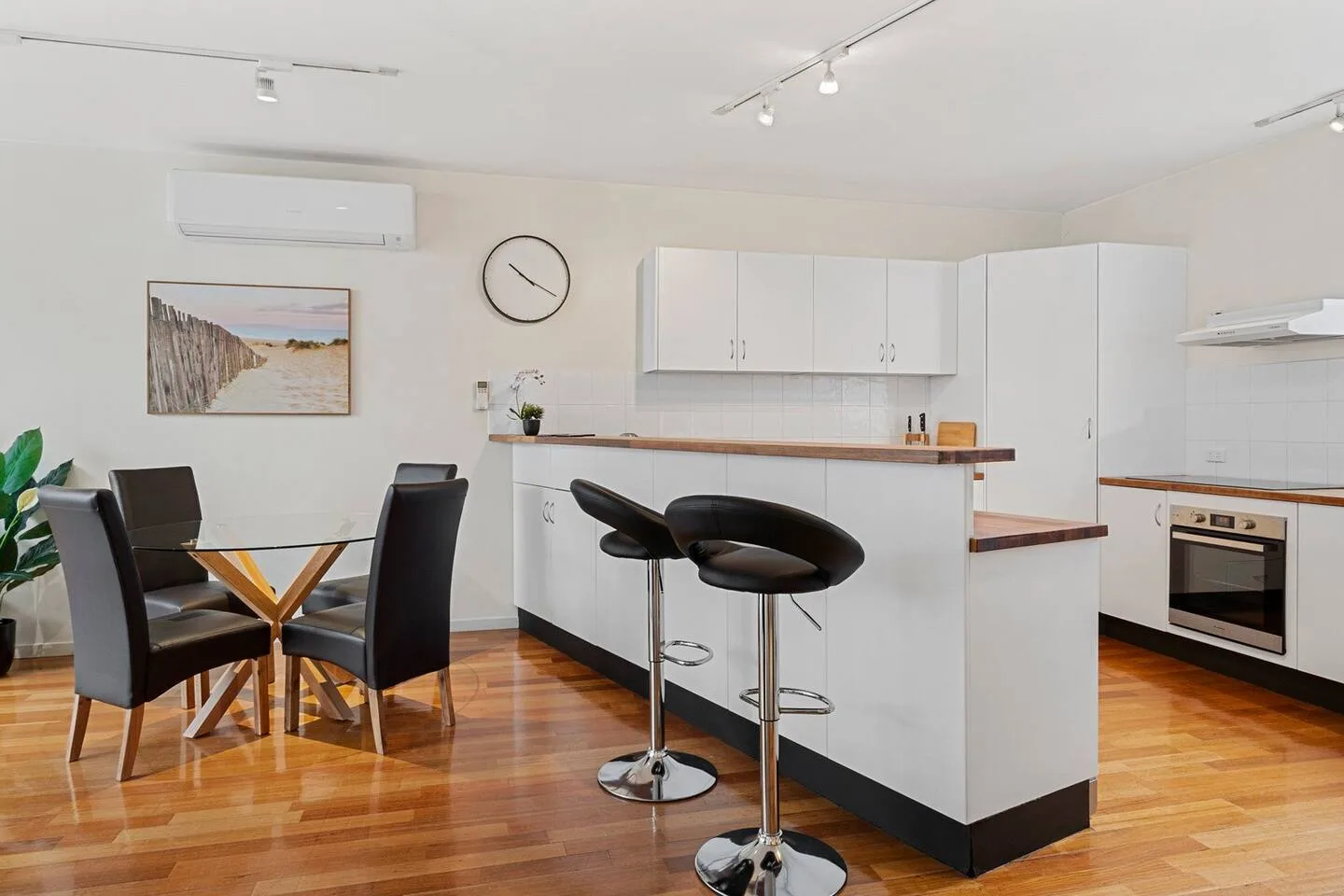 Una cocina luminosa con una mesa de comedor y taburetes junto a la encimera.
