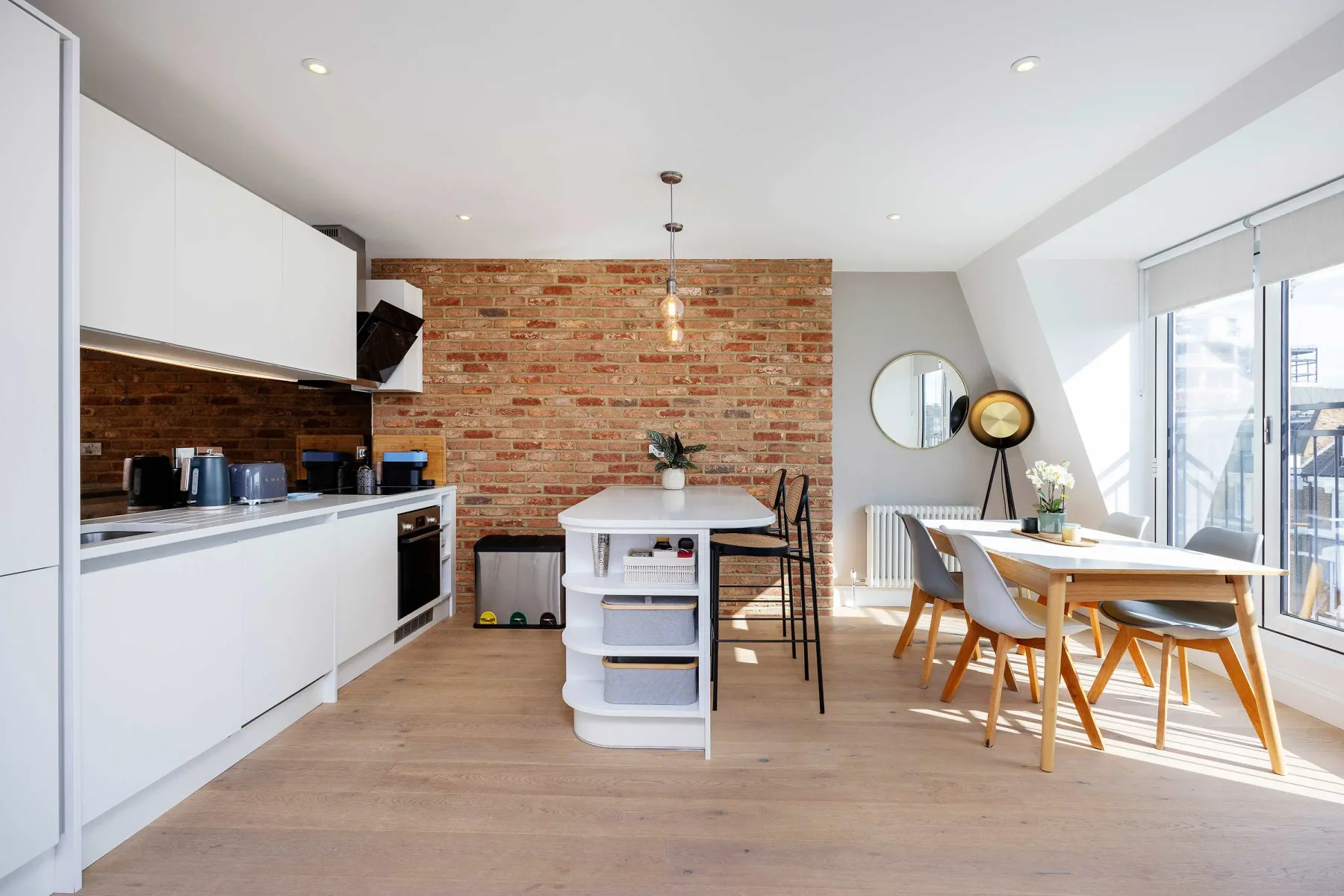 Una cocina y comedor diáfanos y luminosos con una pared de ladrillo.