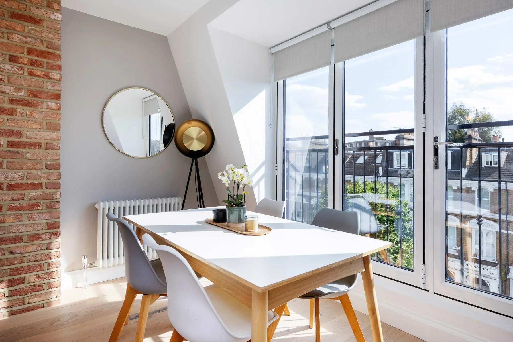 Un comedor luminoso con una mesa, asientos y ventanales que dan a un balcón.