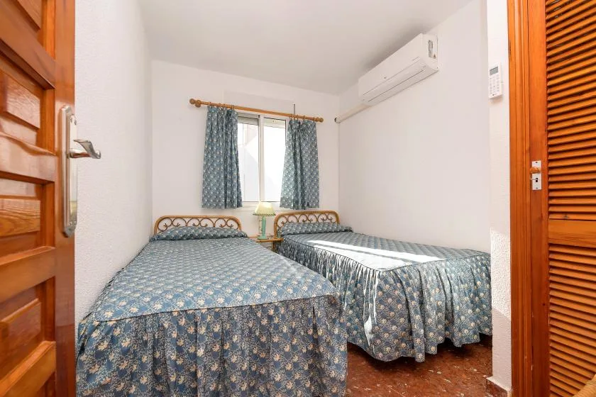 A bedroom with two beds covered in blue patterned bedspreads.