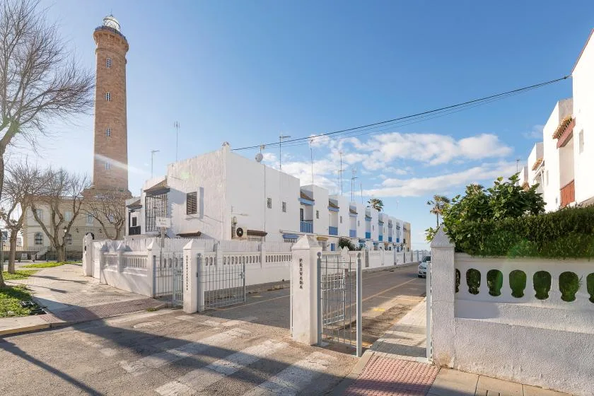 A white residential street with gated entrances and a tall brick tower nearby.