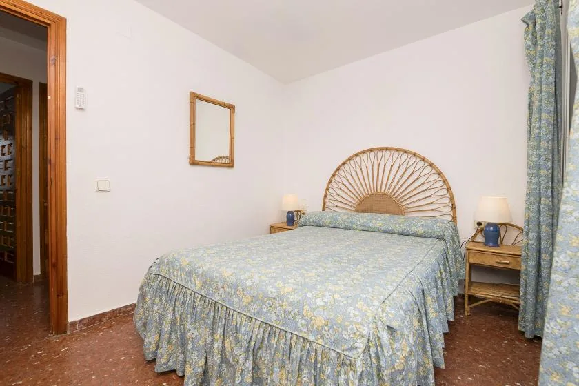 A bedroom with a bed dressed in blue patterned bedding and matching curtains.