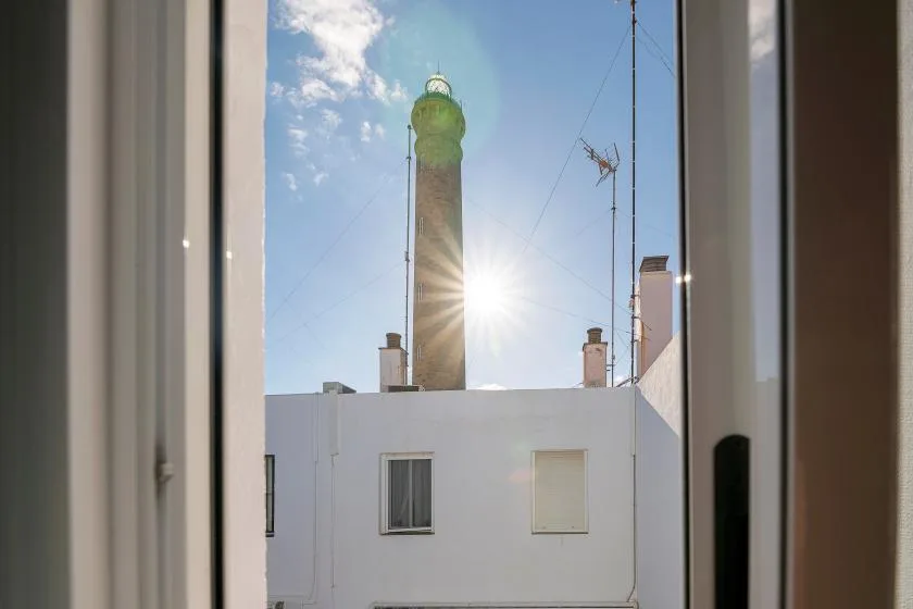 View of a tall tower rising behind a white building, framed by an open window.