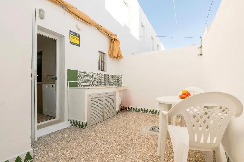 A small outdoor patio with a white table and plastic seating beside the building.