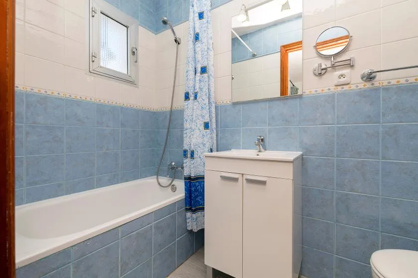 A tiled bathroom with a bathtub, sink, and wall mirror.