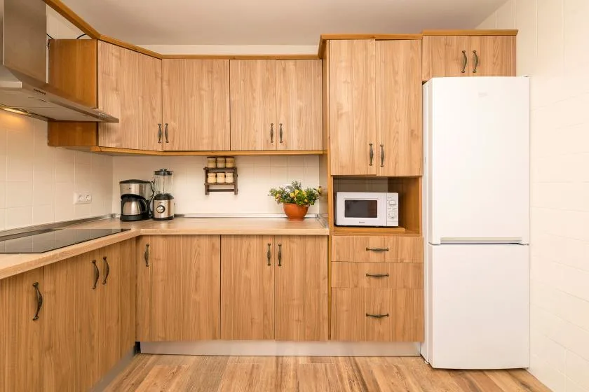 A kitchen with wood cabinets, a microwave, and a refrigerator.