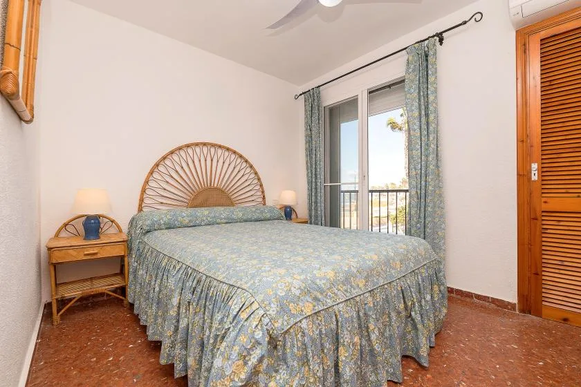A bedroom with a bed beside a window and balcony doors.