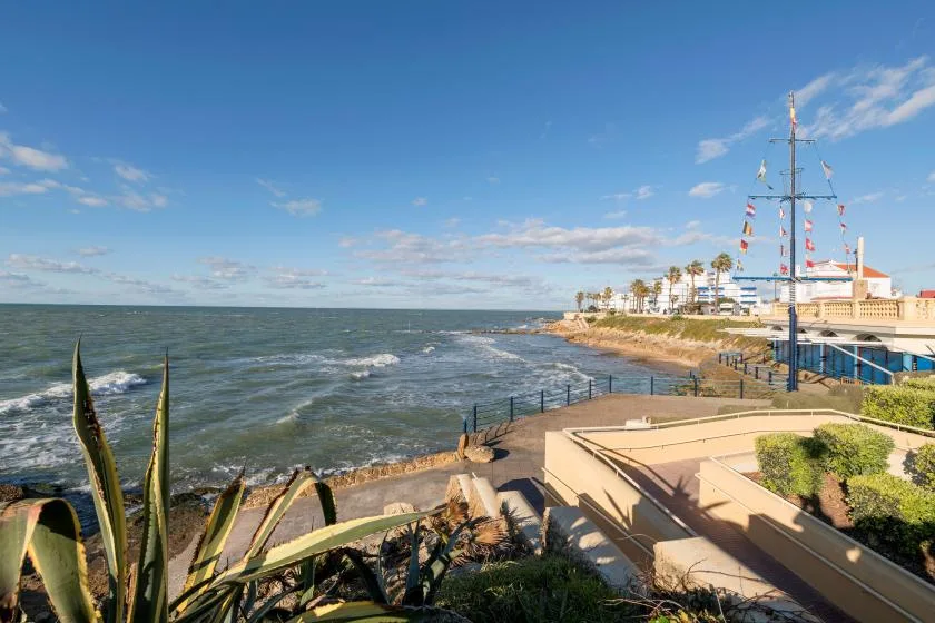 A waterfront promenade overlooks the choppy water beneath a clear blue sky.