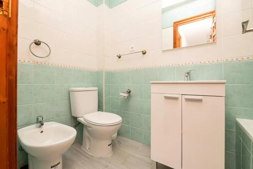A tiled bathroom with a toilet, bidet, and vanity.