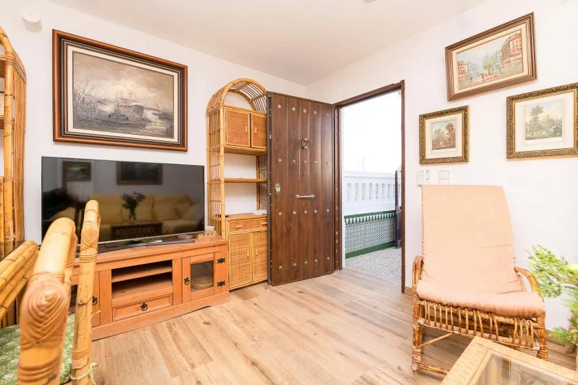 A living room with a television, wooden storage furniture, and an open doorway.