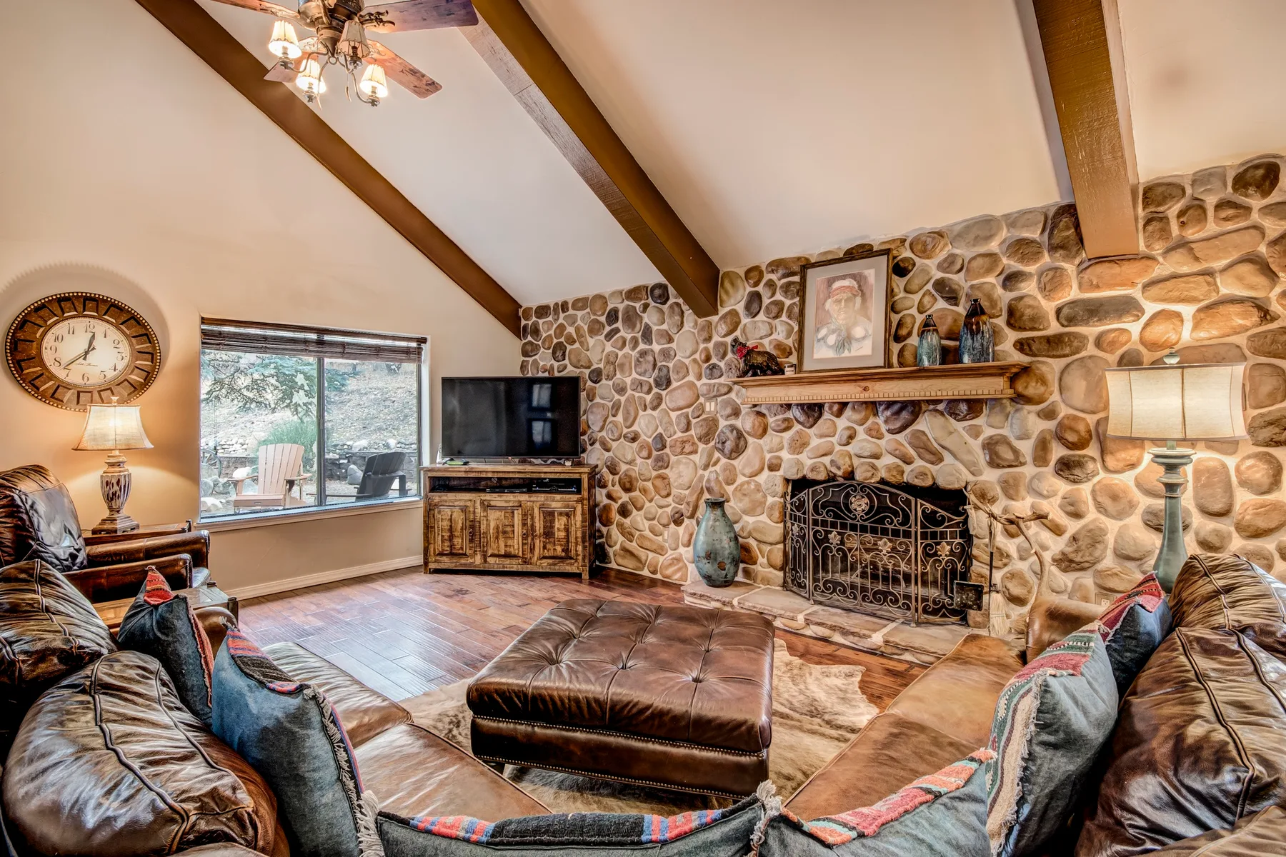 A living room with exposed ceiling beams and a stone fireplace.