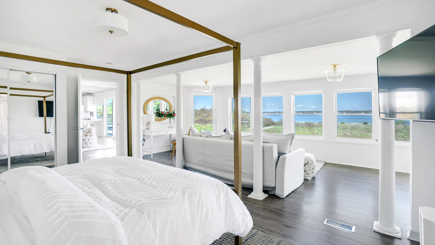 Un dormitorio luminoso se abre a una sala de estar con grandes ventanas hacia el agua.